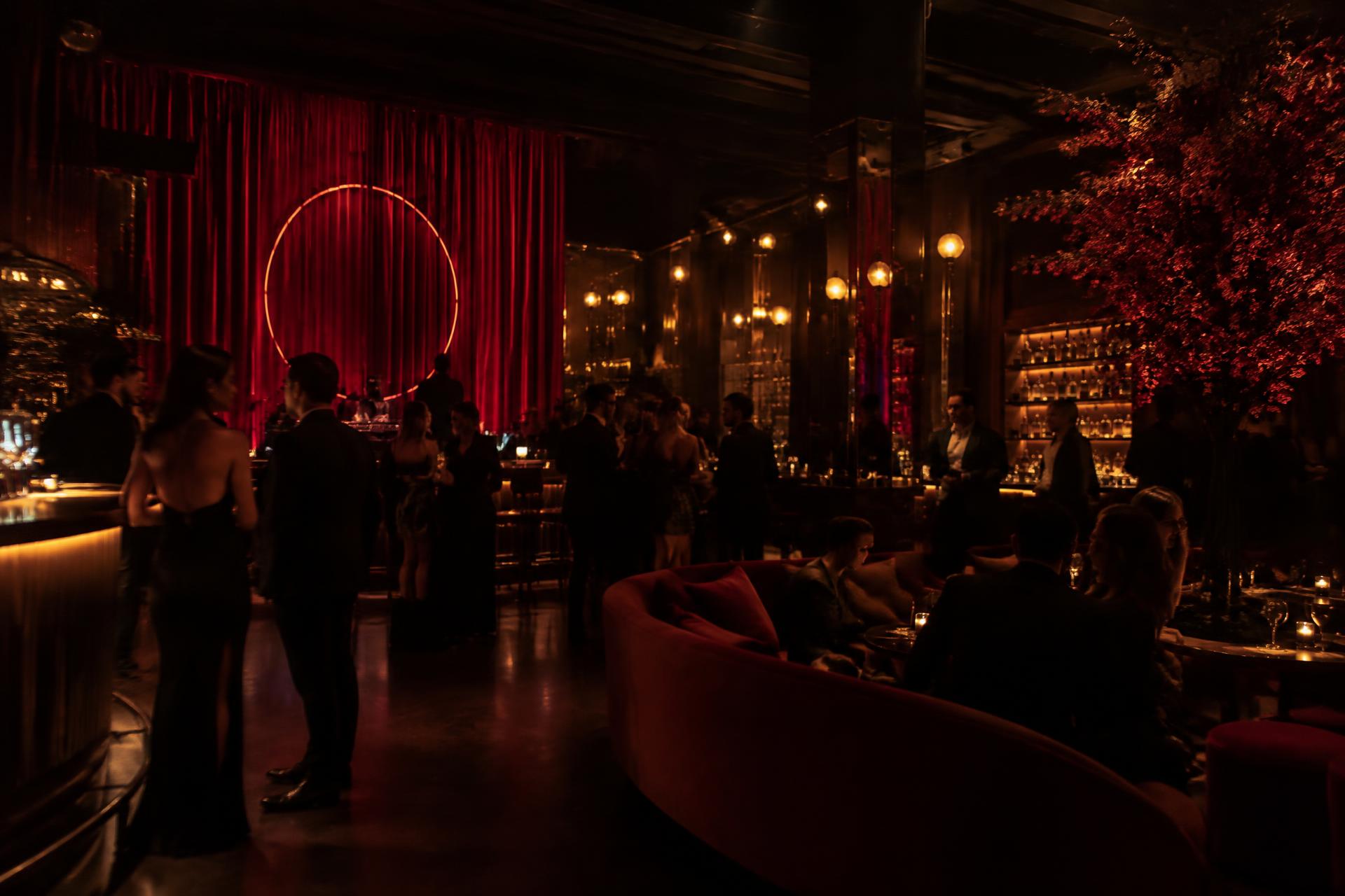 The dimly lit interior of Club Pave at night with guests, warm lighting and deep red decor
